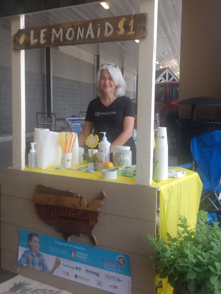 Realty Agents raising charity funds by selling lemonade and wearing a Fathom Realty Shirt