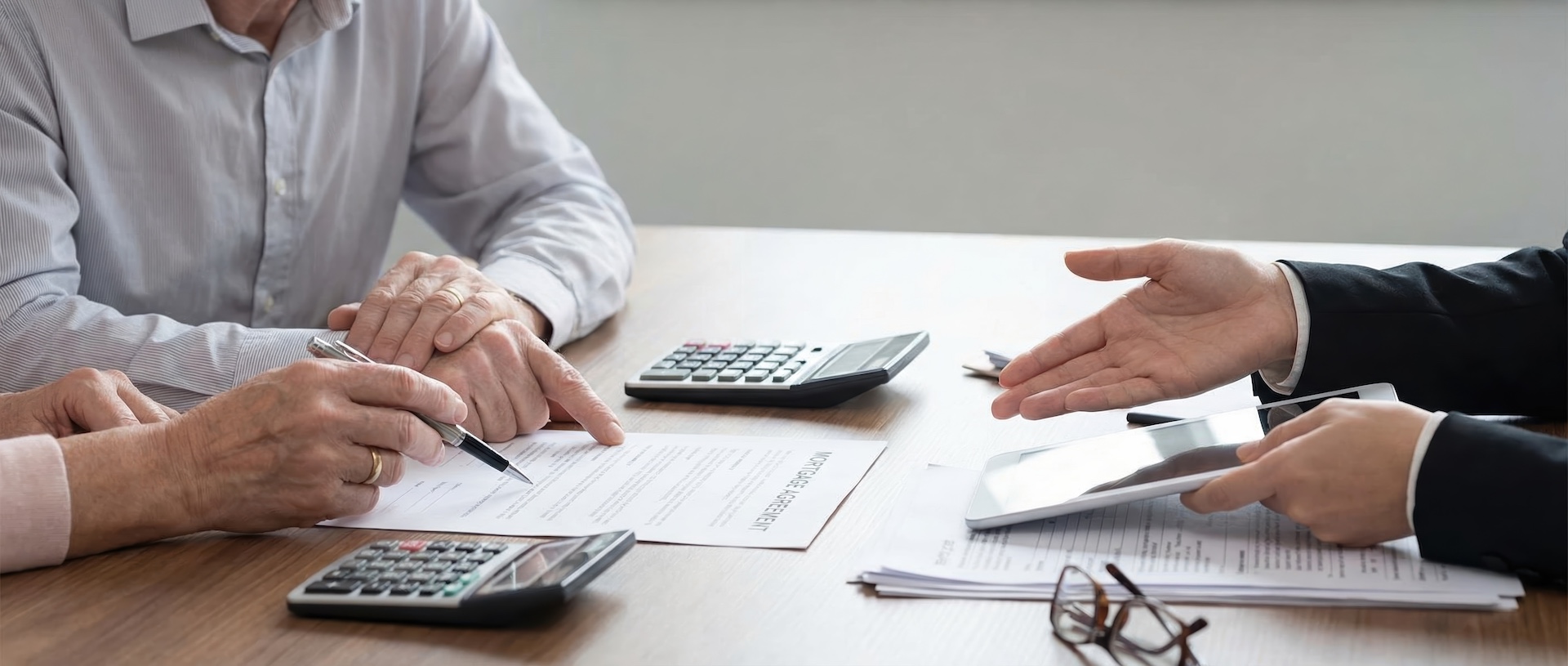 Image of home buyers reviewing mortgage documents across a desk from a loan officer trying to overcome the mortgage lock-in effect.