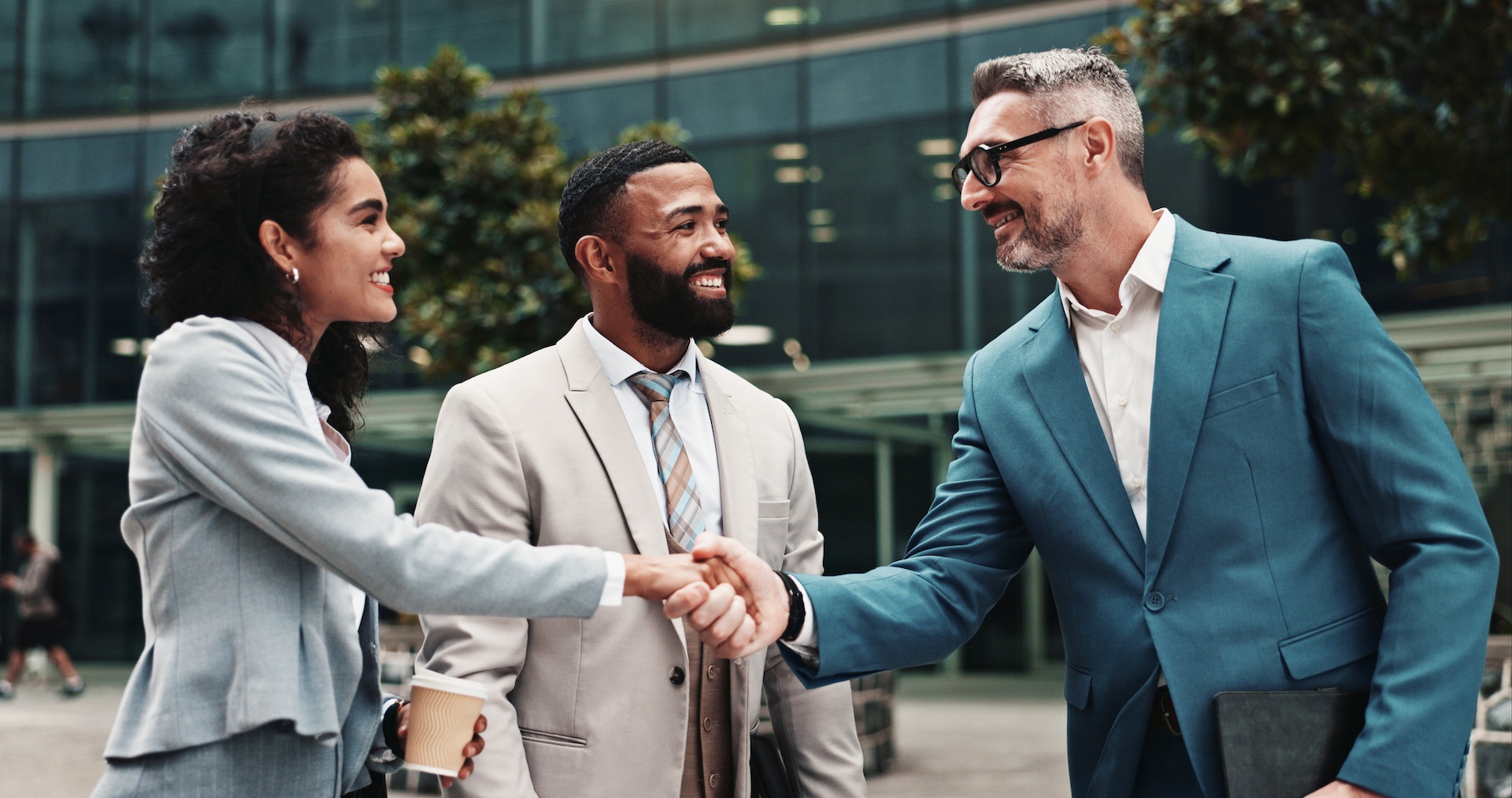 Image depicting real estate business with an agent shaking hands with new clients outside of a home.