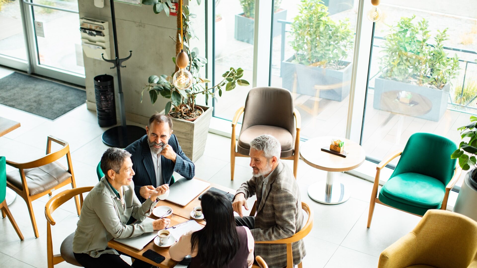 Image of four real estate agents meeting in a table in a coffee shop demonstrates the strength of the referral economy.