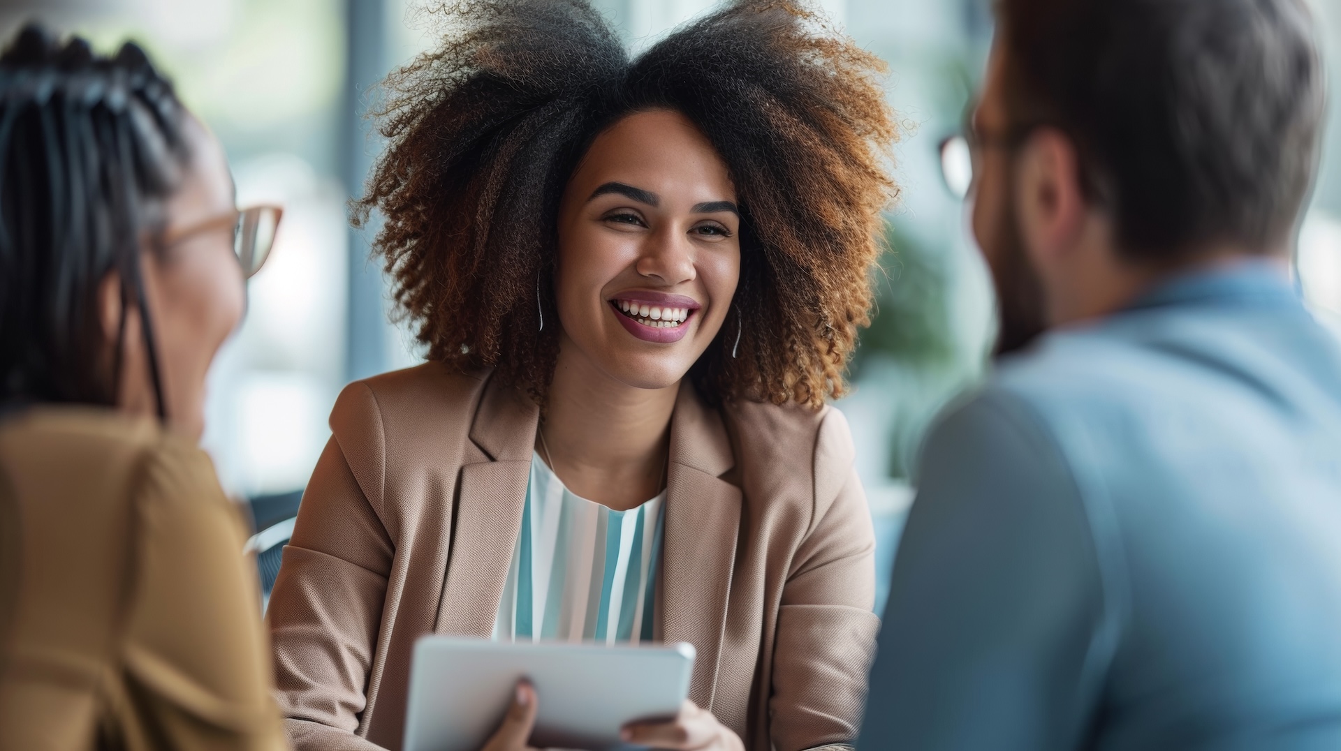 Female agent is show her real estate productivity skills while meeting with new clients and building relationships. Agent with iPad in her hand across the table from a male and female client.